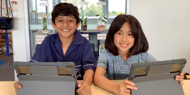 Student collaborating with a peer while using a tablet, highlighting digital learning teamwork and engagement at St Pius X Primary School