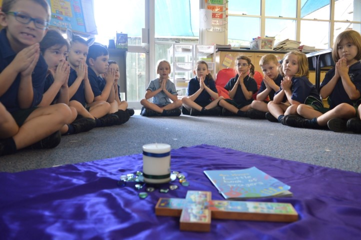 Students seated in a circle during a classroom prayer activity with faith symbols at the centre, highlighting reflection, community and shared Catholic practice at St Pius X Primary School